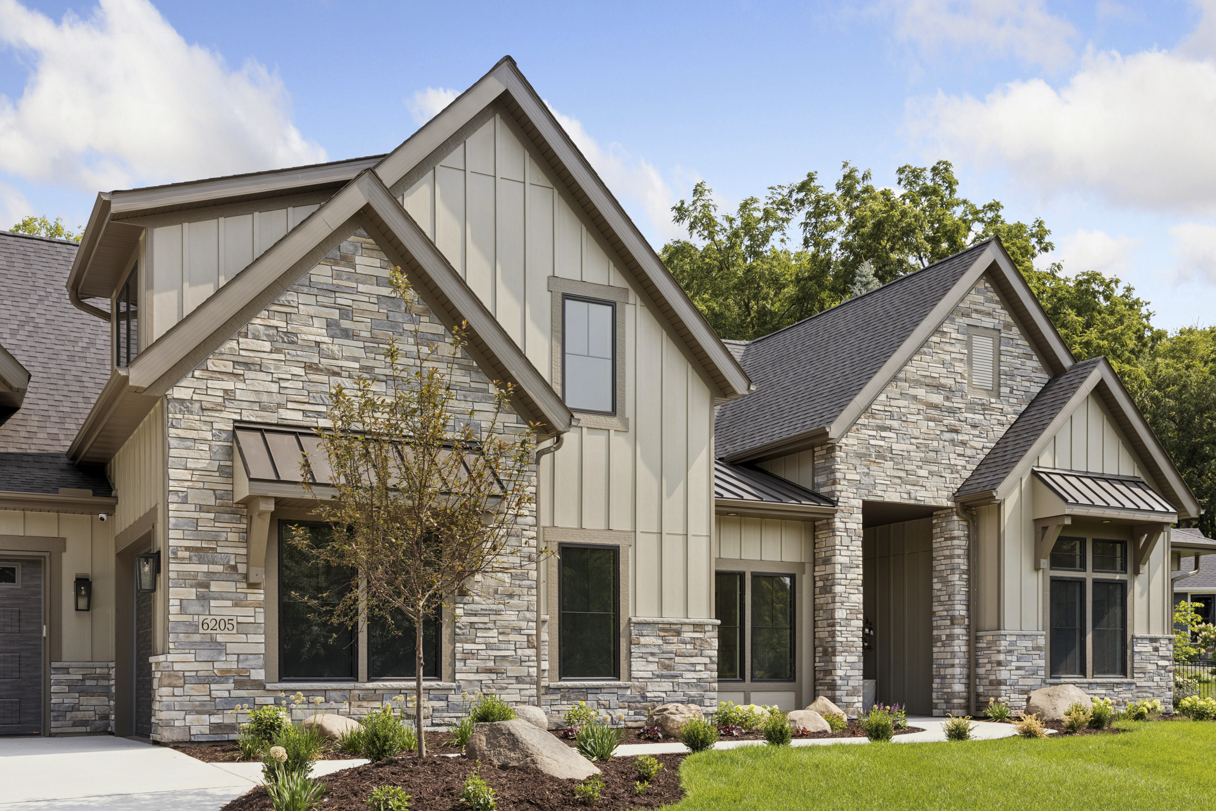 Detailed front elevation of 6205 Hillside with natural stone, board and batten siding, steep gables, and landscaped entry.