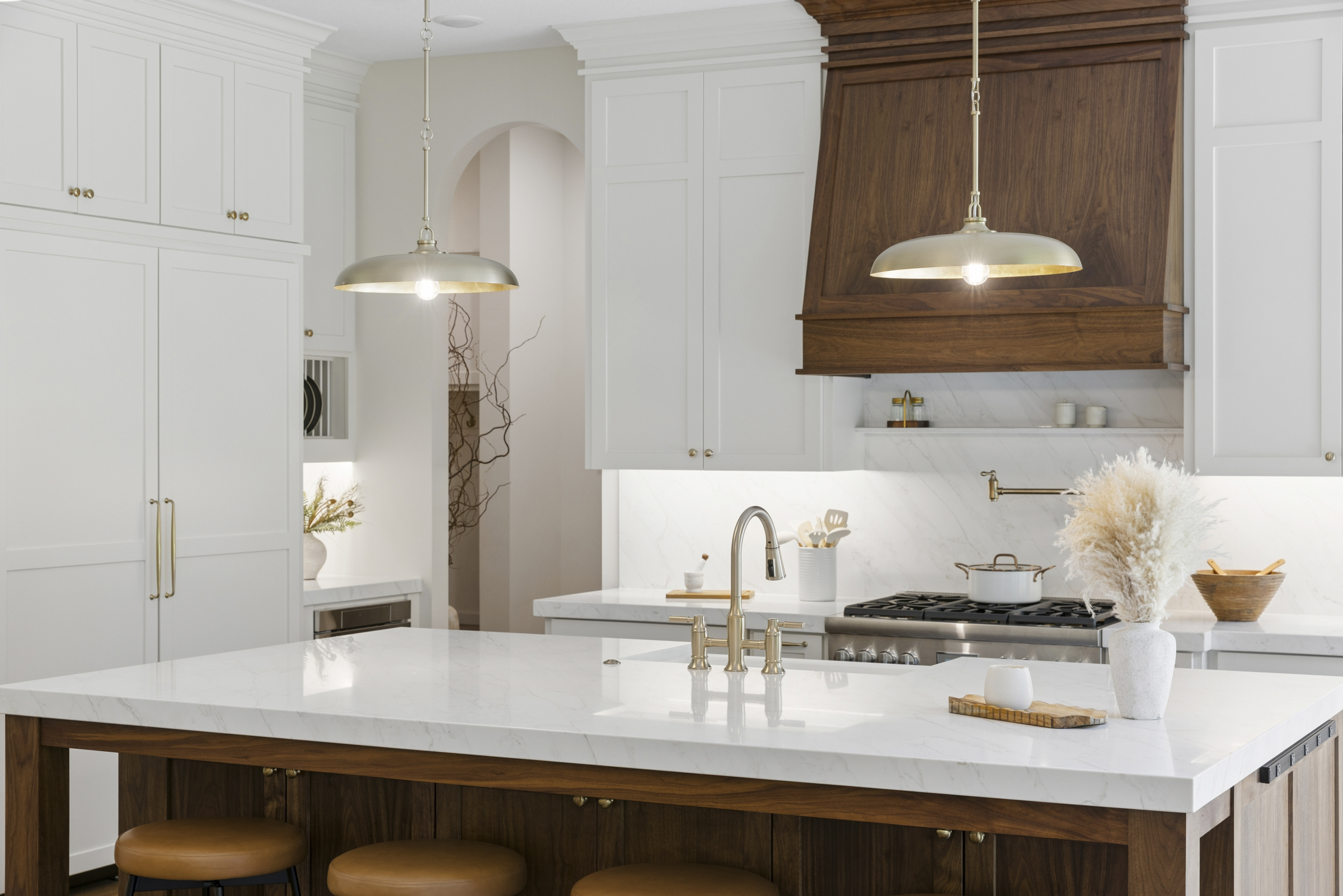 Luxury kitchen at 6205 Hillside with large wood island, white cabinetry, quartz countertops, custom wood range hood, and brass pendant lighting.