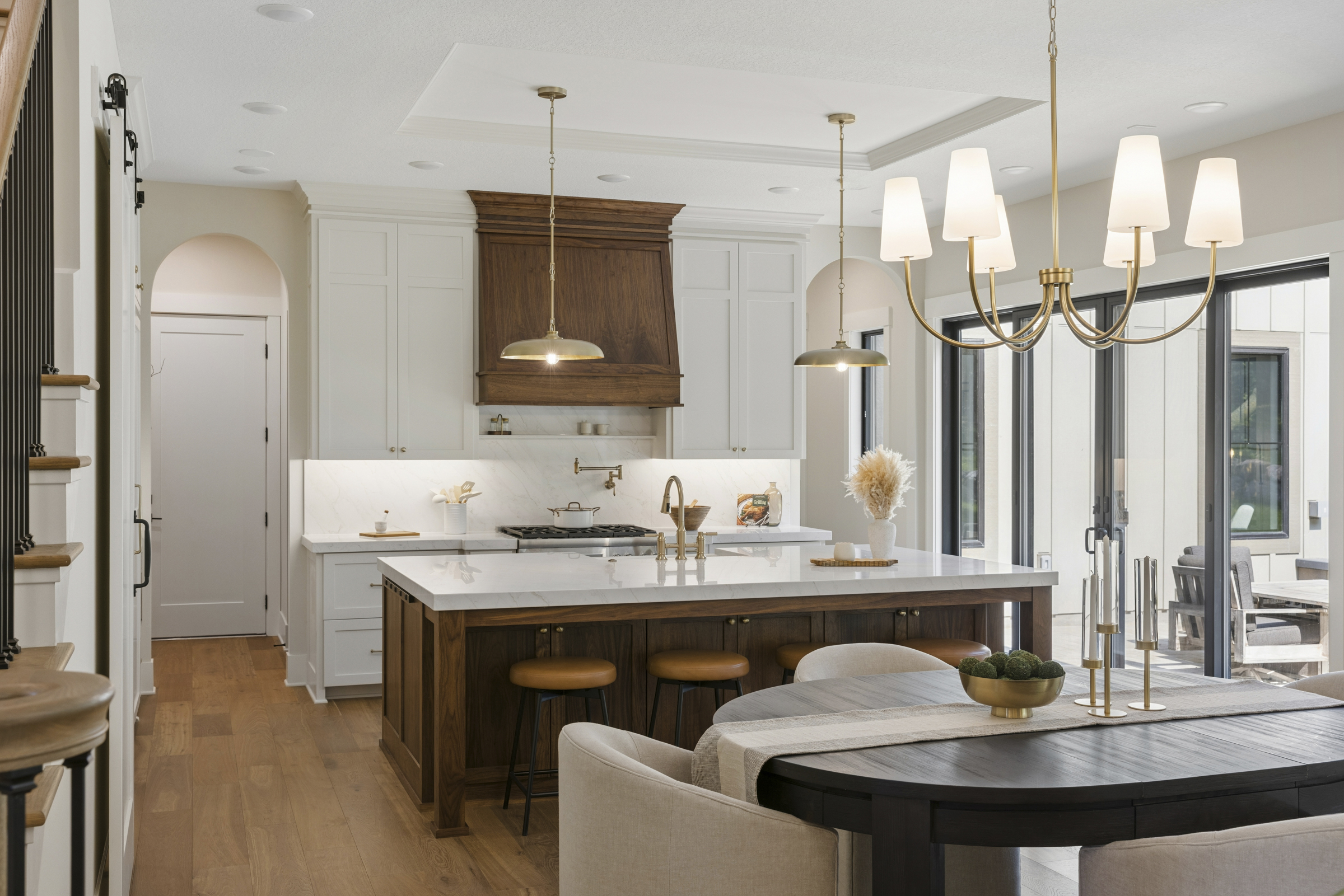 Kitchen and dining area at 6205 Hillside with oversized wood island, custom cabinetry, statement lighting, and sliding doors to the outdoor living area.